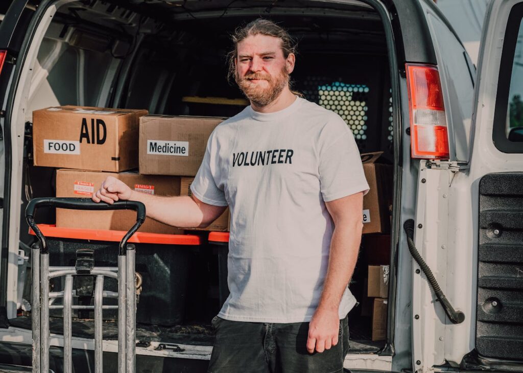 Volunteer standing by a van loaded with aid supplies, ready to serve the community.