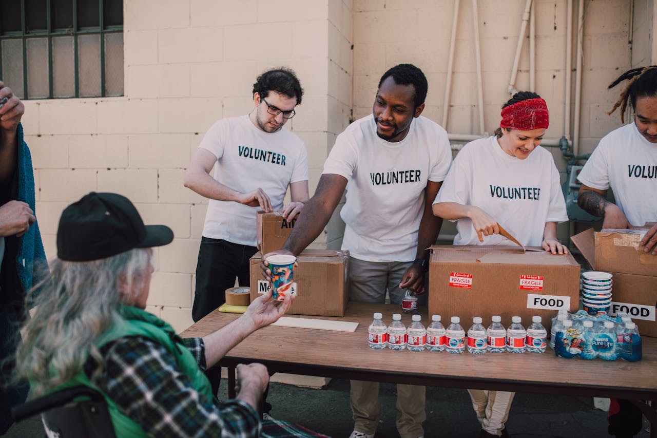 Volunteers distribute food and drinks to the needy at an outdoor charity event.